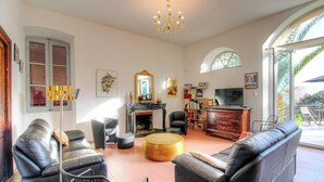 A living room with a fireplace, a television, and a bookshelf. - Villa Belvédère - AJACCIO (AJACCIO)