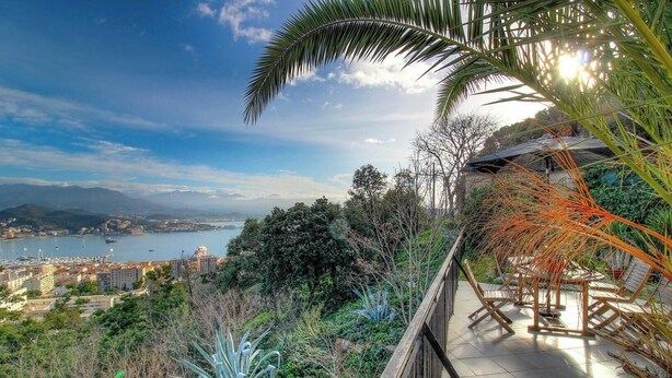 A balcony with a view of a coastal city, including buildings and a body of water. - Villa Belvédère - AJACCIO (AJACCIO)