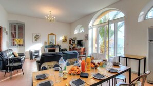 A spacious living area with a dining table set for breakfast, a sofa, and a fireplace. - Villa Belvédère - AJACCIO (AJACCIO)