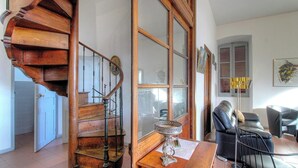 A spiral staircase, a dining table with a decorative bowl, and a sofa in a room with large windows and a view of the outside. - Villa Belvédère - AJACCIO (AJACCIO)