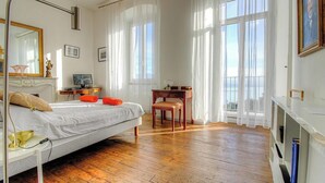 A bedroom with a bed, a desk, a chair, a television, and a large window. - Villa Belvédère - AJACCIO (AJACCIO)