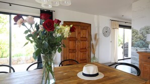 Een eettafel met een bloevas, een hoed en een houten deur in een kamer met uitzicht.