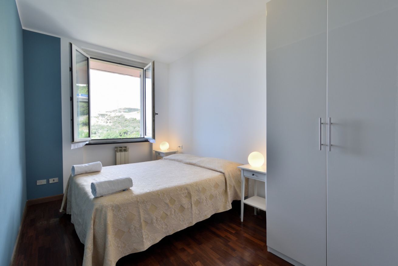 Una camera da letto con un letto, una finestra, un comodino con una lampada e un armadio.