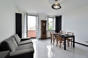 Un soggiorno moderno con un divano, un tavolo da pranzo, sedie, una sveglia e una finestra.
