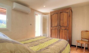 Une chambre avec un lit, un climatiseur, une armoire et une chaise.