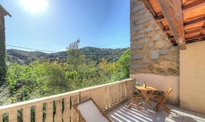 Un balcon donnant sur un paysage verdoyant, avec une table et des chaises.