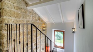 A staircase with stone walls, a wooden door, and wall-mounted lights. - Casa Andressi - Figari (Figari)
