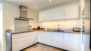 A modern kitchen with white cabinets, stainless steel appliances, and a built-in oven. - Casa Andressi - Figari (Figari)