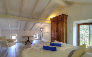 Ein Schlafzimmer mit einem Bett, einem Sessel, einem Tisch, einer Lampe und einem Kleiderschrank.