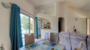 Un soggiorno moderno con un tavolo in vetro, un divano e una cucina sullo sfondo.