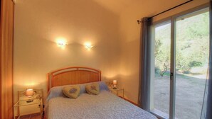 Una camera da letto con un letto, due lampade da comodino, un comodino e vista attraverso un'ampia finestra.
