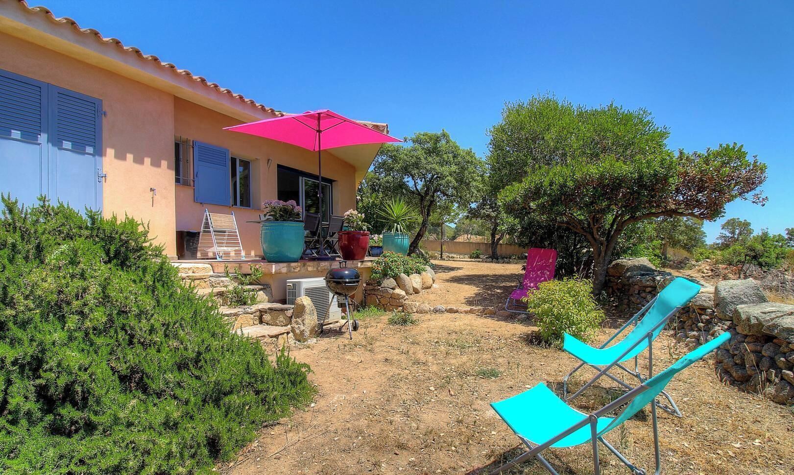 A house with a patio, outdoor furniture, and potted plants.
