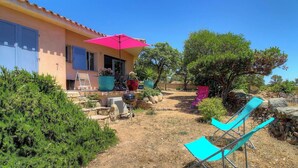 Una casa con patio, mobili da esterno e piante in vaso.