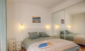 A bedroom with a bed, bedside tables, a mirror, and a painting on the wall. - Casa Pianosa - LUCCIANA (LUCCIANA)
