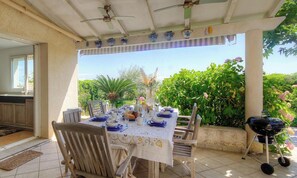 An outdoor dining area with a table set for four, surrounded by chairs, a ceiling fan, and a grill. - Casa Pianosa - LUCCIANA (LUCCIANA)
