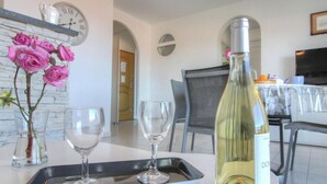 Zona pranzo con tavolo imbandito per due, una bottiglia di vino e un vaso di rose rosa.