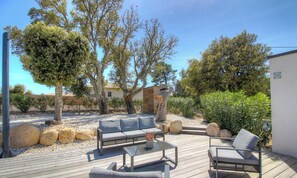 An outdoor patio with a wooden deck, a sofa, a coffee table, and a chair. - Villa Corsu - PORTO VECCHIO (PORTO VECCHIO)