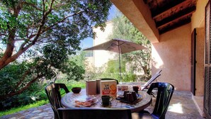 Une terrasse extérieure avec une table, des chaises, un parasol et une boîte de biscuits.