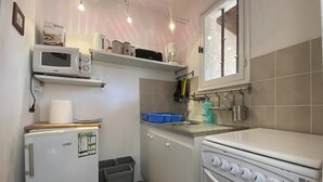 Une cuisine compacte équipée d’un réfrigérateur, d’un four à micro-ondes, d’une cuisinière et d’une petite poubelle.