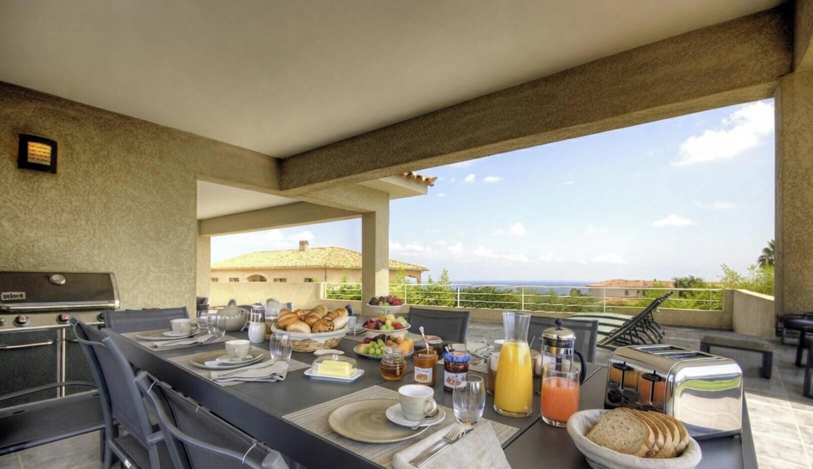 Zona de menjador a l'aire lliure amb una barbacoa, bufet de l'esmorzar i vista al paisatge.