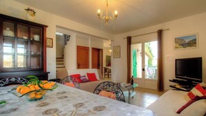 Una habitación con cama, una mesa de comedor con naranjas, un televisor y vistas al exterior.