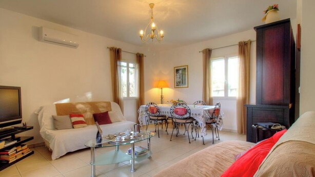 Una sala de estar con sofá, televisión, mesa de centro de vidrio, mesa de comedor con sillas y chimenea.