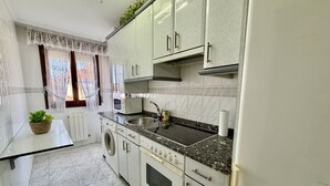 Una cucina con lavatrice, forno, microonde, lavello e pensili.