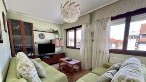 Un soggiorno con due divani verdi, un tavolino in legno, una televisione e una finestra con tende.