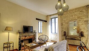 Ein Wohnzimmer mit Kamin, Fernseher, Esstisch und einer Steinwand.