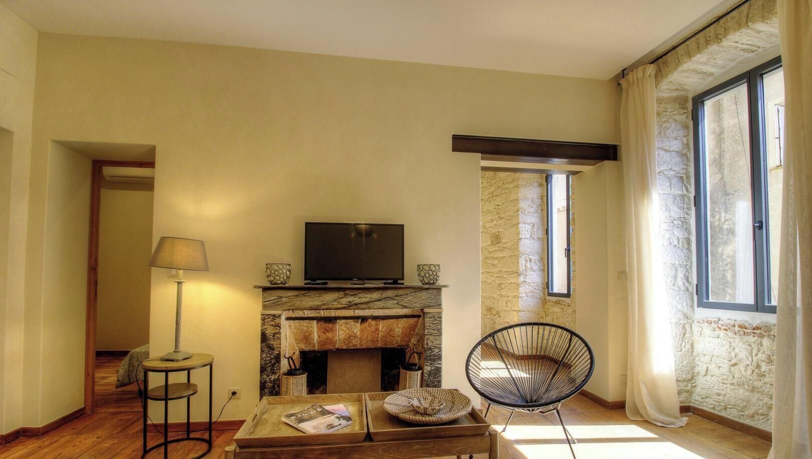A living room with a fireplace, a television, a lamp, and a chair.