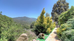 Un jardín con un sendero, una roca grande y vistas a las montañas.
