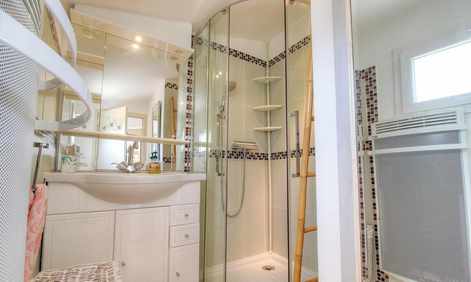 Un baño con ducha de vidrio, un lavabo blanco y un espejo encima.