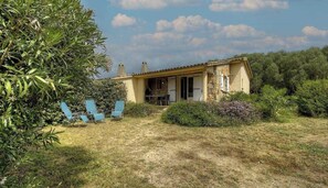 Ein Haus mit einer Stein-Fassade, einer überdachten Veranda und einem Garten mit Gartenmöbeln.