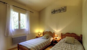Ein Schlafzimmer mit zwei Betten, einem Heizkörper, einem Fenster mit Vorhängen und einem Wandbild.