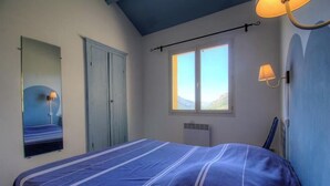 Et soveværelse med seng, vindue, radiator og et spejl.