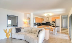 A modern living room with a sofa, a dining area with a table and chairs, a kitchen with wooden cabinets and appliances, and a staircase leading to another level. - Stella di Mare - COTI CHIAVARI (COTI CHIAVARI)