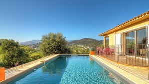 A swimming pool with a wooden deck, a covered patio area, and a view of distant hills. - Villa chjara - SAINTE LUCIE DE PORTO VECCHIO (SAINTE LUCIE DE PORTO VECCHIO)