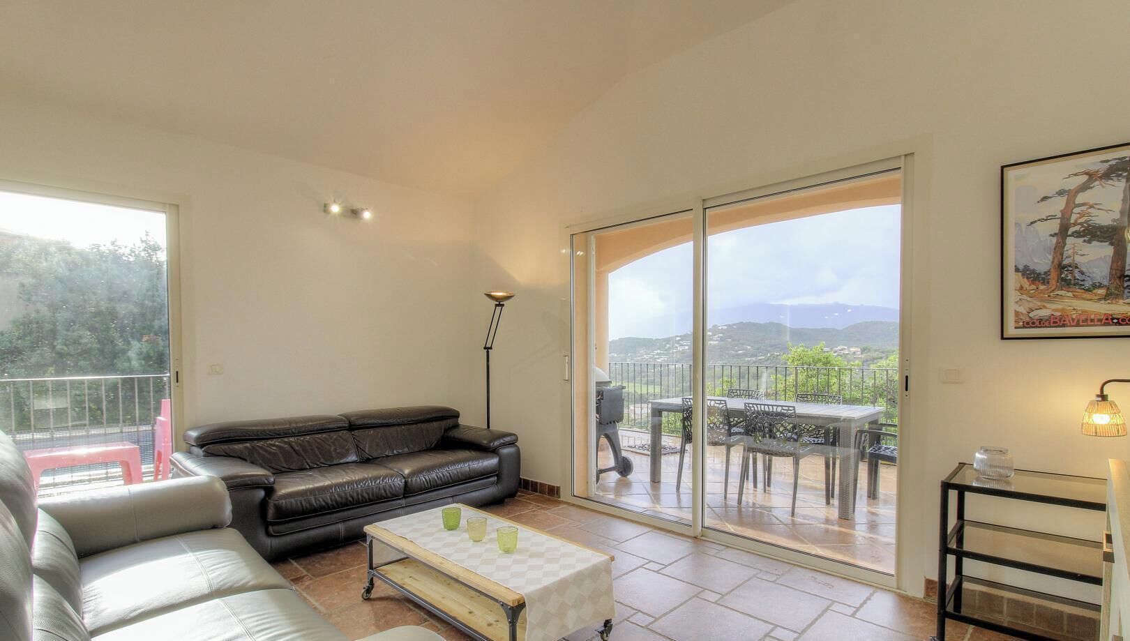 A living room with a sofa, a coffee table, and a balcony with a table and chairs.