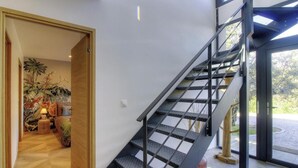 Ein modernes Interieur mit Treppe, Holzboden und Blick durch eine Glastür.