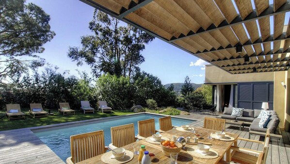 A poolside area with a table set for dining, lounge chairs, and a covered seating area. - Valere 2 - SAINTE LUCIE DE PORTO VECCHIO (SAINTE LUCIE DE PORTO VECCHIO)