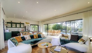 Ein großzügiges Wohnzimmer mit einer Sofagarnitur, einem Couchtisch und Blick auf die Außenpatio-Terrasse.