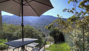 A table and chairs under an umbrella, overlooking a mountainous landscape. - Coté village-Nelly - CRISTINACCE (CRISTINACCE)