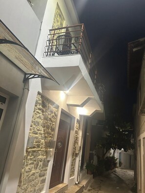 Ein zweistöckiges Gebäude mit einer Steinaußenfassade, einem Balkon mit Metallgeländern und einem gut beleuchteten Eingang.