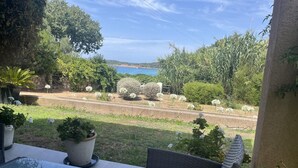 Eine Terrasse mit Korbmöbeln, Blumentöpfen und Blick auf eine Küstenlandschaft.