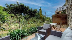 Eine Terrasse mit Korbmöbeln, einem Glastisch und einem Holzzaun.