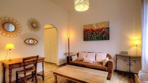 Ein Wohnzimmer mit einem Holzesstisch, einer Couch, einem Couchtisch, einer Lampe und einem Bild an der Wand.