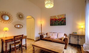 Ein Wohnzimmer mit einem Holzesstisch, einer Couch, einem Couchtisch, einer Lampe und einem Bild an der Wand.
