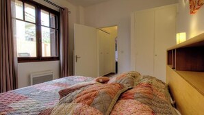 Ein Schlafzimmer mit Bett, Kleiderschrank, Tür und Fenster.