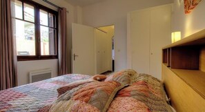 Ein Schlafzimmer mit Bett, Kleiderschrank, Tür und Fenster.