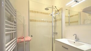 Ein modernes Badezimmer mit Duschkabine aus Glas, einem weißen Waschbecken und einem Handtuchhalter.
